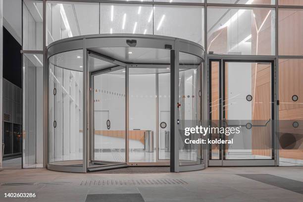 revolving door and lobby of modern office building at night - revolving door ストックフォトと画像