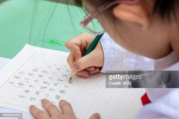 Student writes with pencil during a calligraphy competition at a primary school on June 13, 2022 in Hohhot, Inner Mongolia Autonomous Region of China.