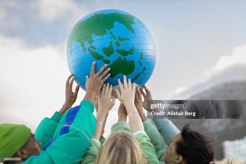 Group of teenagers holding up the world