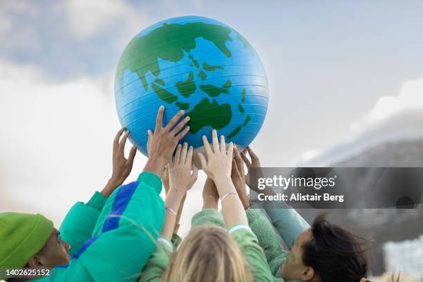 group of teenagers holding up the world - verantwoordelijkheid stockfoto's en -beelden