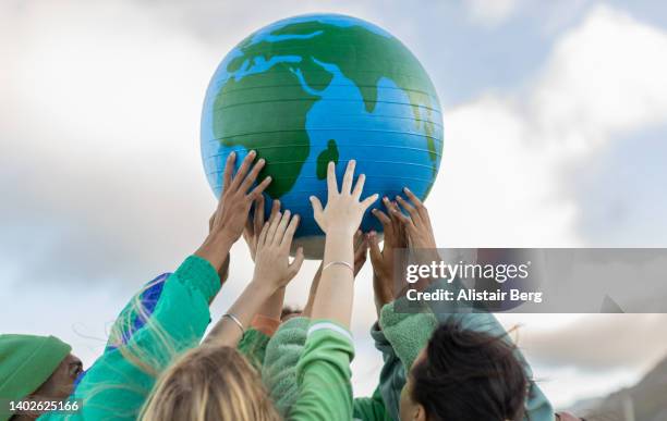 group of teenagers holding up the world - earth activist stock pictures, royalty-free photos & images