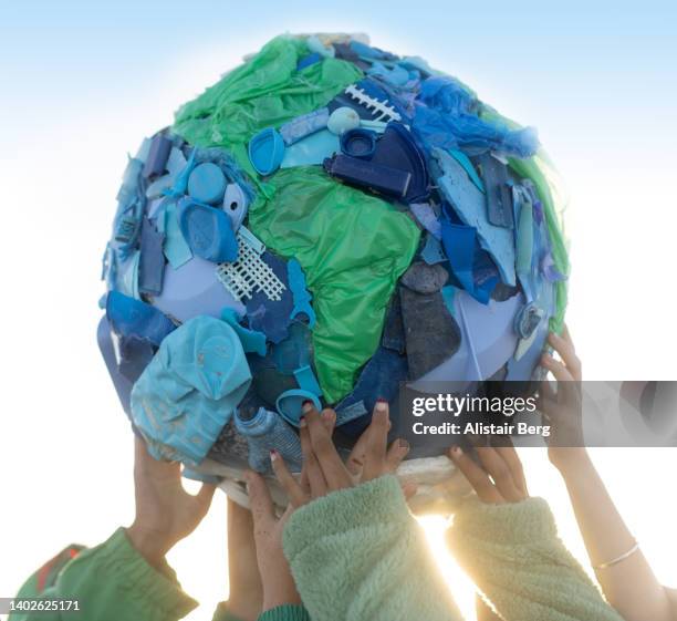 group of teenagers holding up a world made of single use plastic - teenager alter 個照片及圖片檔