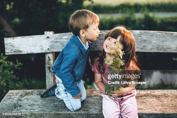 a little boy gives a bouquet of wildflowers to a little girl. - man giving flowers stock-fotos und bilder