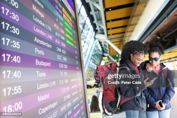 two young backpacking women at airport - departure board front on fotografías e imágenes de stock