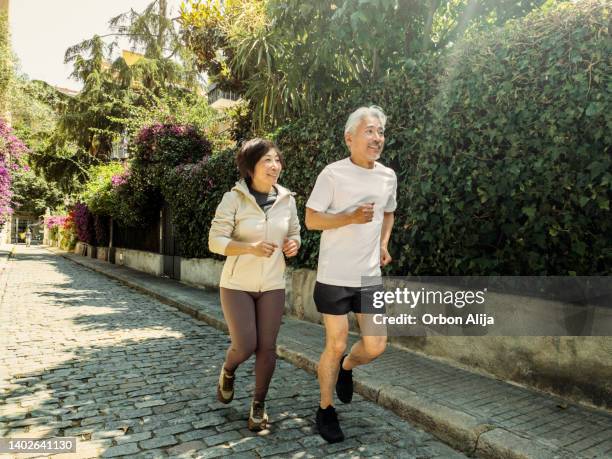 couple running in the city - asian senior couple stock pictures, royalty-free photos & images