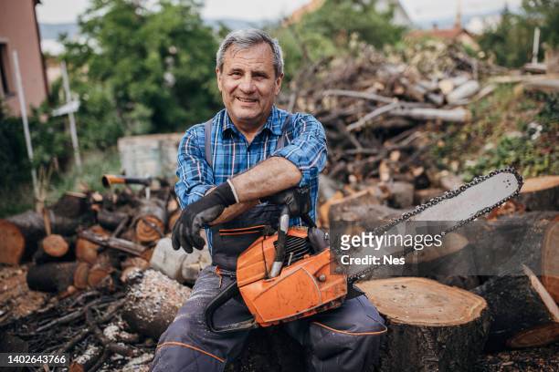 porträt eines lächelnden holzfällers mit kettensäge - forestry worker stock-fotos und bilder