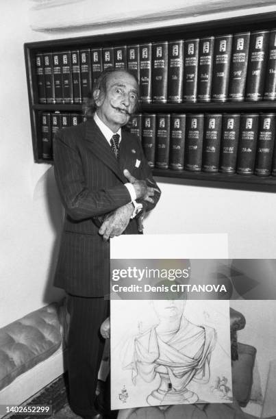 Le peintre Salvador Dali avec un dessin de Charles de Gaulle en empereur dans sa maison de Cadaqués le 28 septembre 1974.