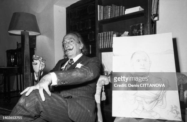 Le peintre Salvador Dali avec un dessin de Charles de Gaulle en empereur dans sa maison de Cadaqués le 28 septembre 1974.