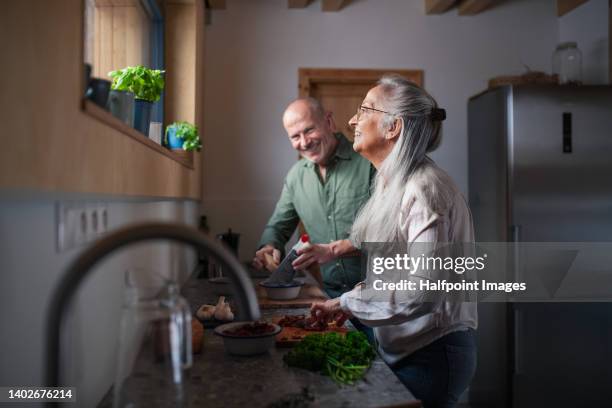 senior couple preparing meal together in their kitchen. - alter mann kocht stock-fotos und bilder