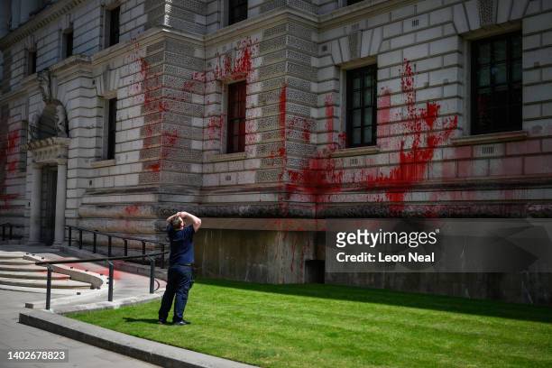 Man surveys the damage after red paint was thrown onto the front of the Treasury building on June 13, 2022 in London, England. Members of the "Just...