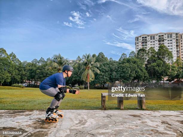 asian chinese mid adult man learning inline skating in public park during weekend morning - blade stock pictures, royalty-free photos & images