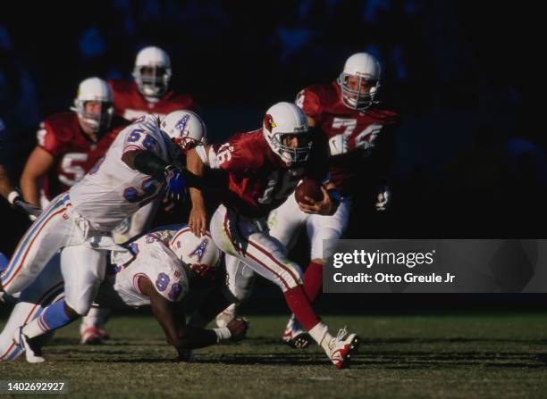 Jake Plummer, Quarterback for the Arizona Cardinals runs with the football to evade the tackle from Joe Bowden and Pratt Lyons of the Tennessee...
