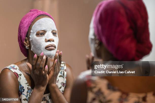 close-up of a woman applying facial mask while looking in mirror - mascarilla stock pictures, royalty-free photos & images