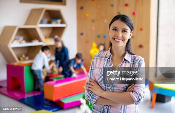 happy elementary school teacher smiling in the classroom - demonstrating imagens e fotografias de stock