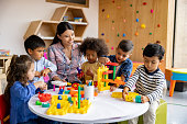 Teacher with a group of elementary students playing with toy blocks