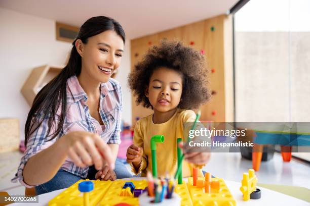 happy teacher playing with a girl in the classroom - preschool age stockfoto's en -beelden