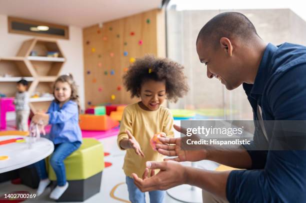 happy elementary students playing with slime and showing it to the teacher - preschool stockfoto's en -beelden