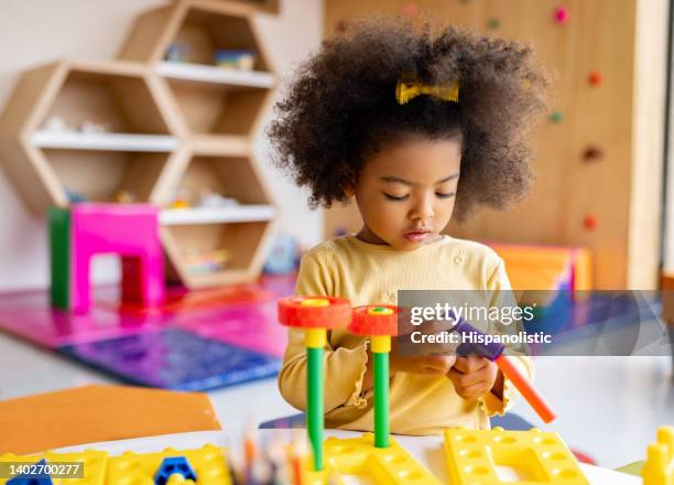 african american girl playing with building blocks at the school - playing toy men stockfoto's en -beelden