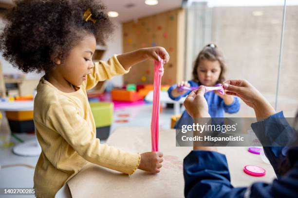 girls playing with slime in class at the school - preschool classroom stockfoto's en -beelden