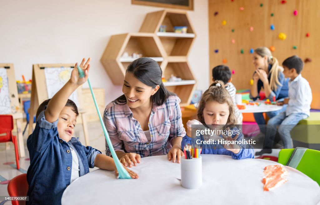 Happy kids playing with slime at the school and showing the teacher
