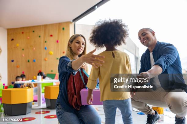 happy parents greeting their daughter while picking her up from school - nursery school stockfoto's en -beelden