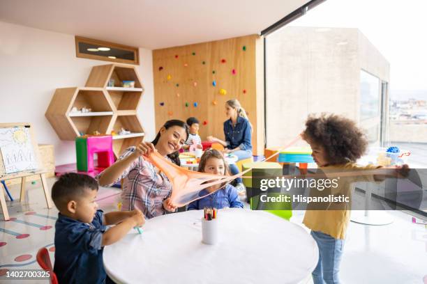 teacher having fun with her students playing with slime at the school - kid presenting stock pictures, royalty-free photos & images