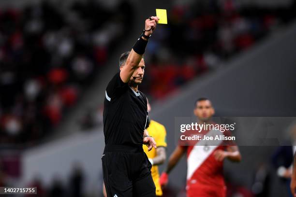 Referee Slavko Vincic shows Nathaniel Atkinson of Australia a yellow card in the 2022 FIFA World Cup Playoff match between Australia Socceroos and...