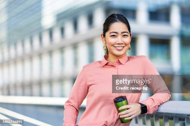 portrait of beautiful young businesswoman holding reusable bottle in front of office building - reusable water bottle office stock pictures, royalty-free photos & images