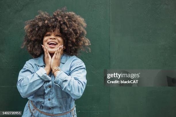 fashionable young african-american woman posing in front of the green wall - adult retainer stockfoto's en -beelden