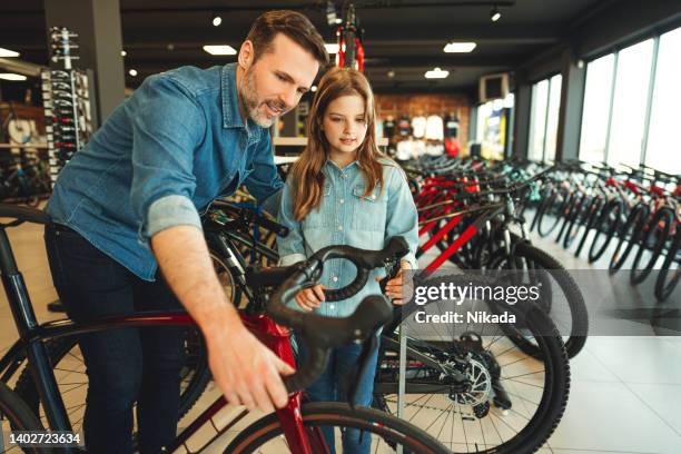 vater und tochter im fahrradladen - sport shop stock-fotos und bilder