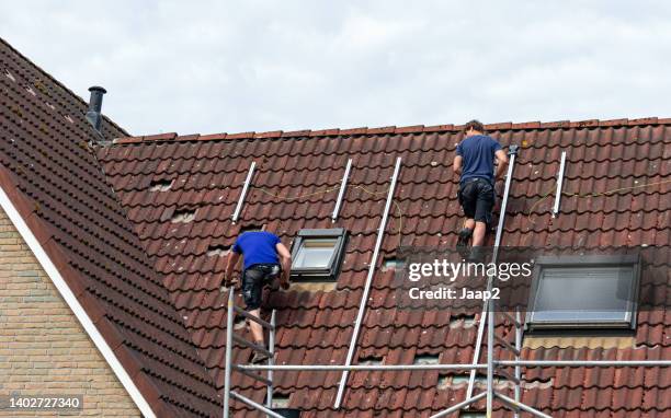 two man on a tiled roof preparing the installation of solar panels - skylight stock pictures, royalty-free photos & images