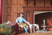 Young Elizabethan gentleman sat by the fire with his dog, 16th Century Baronial residence