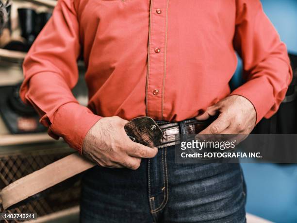 hands of mature latin man getting dressed as mexican cowboy - western shirt stockfoto's en -beelden