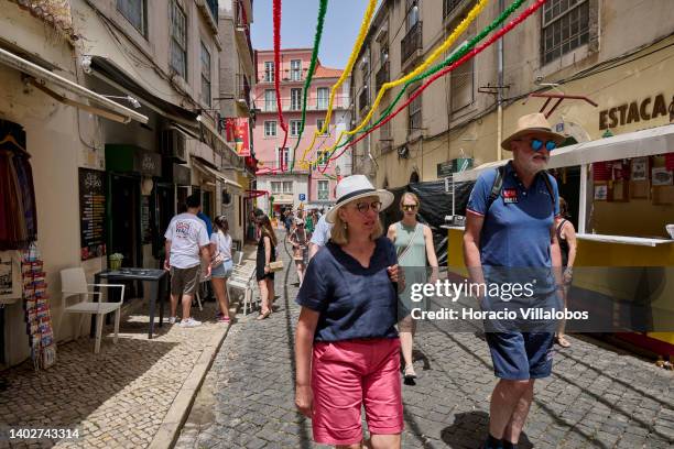 Tourists walk during Santo Antonio city's festivities in one of the narrow streets in the old quarter of Alfama on June 13, 2022 in Lisbon, Portugal....