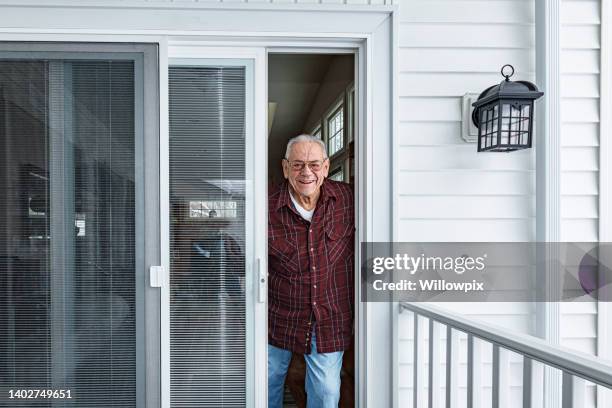 anciano mirando desde la puerta principal de su casa - sliding door fotografías e imágenes de stock