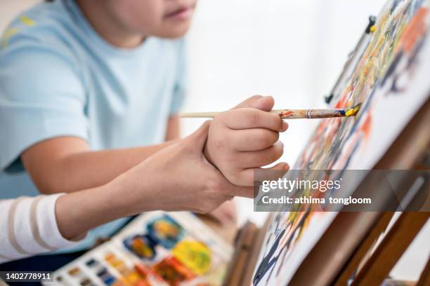 a young art teacher woman helps autistic children to paint on canvas. - autistic child stock pictures, royalty-free photos & images