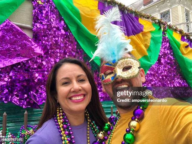 happy latin tourists friends / heterosexual couple celebrating mardi gras in new orleans dressing necklace and masks - mardi gras fun in new orleans stockfoto's en -beelden