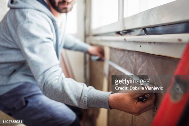 industrial worker measuring heater placed on a wall in a new apartment - meter unit of length stock pictures, royalty-free photos & images