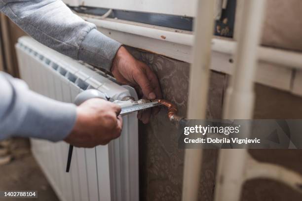 industrial worker measuring heater placed on a wall in a new apartment - hot and new stock pictures, royalty-free photos & images