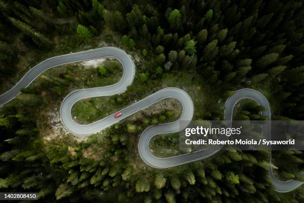 car traveling on winding mountain road in a forest, overhead view - virage photos et images de collection