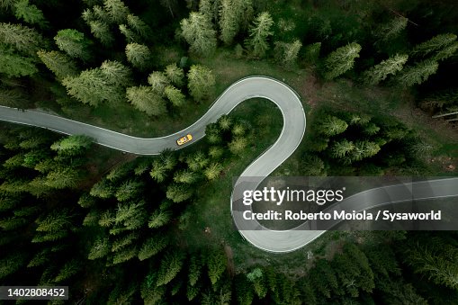 Aerial view of car traveling on winding mountain road in a forest Aerial view of car traveling on winding mountain road in a forest