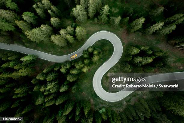 aerial view of car traveling on winding mountain road in a forest - ripresa di drone foto e immagini stock