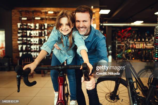 father and daughter testing racing bike in bike store - new sport content stock pictures, royalty-free photos & images