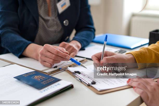close-up of filling in paper form and ukrainian passport. - emigration and immigration foto e immagini stock