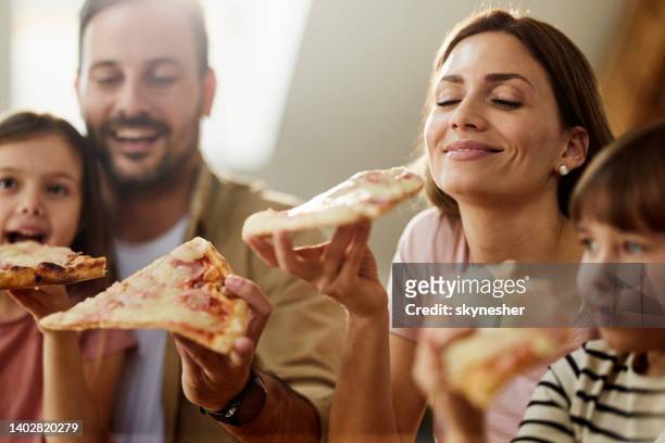 familia joven y feliz comiendo pizza para el almuerzo en casa. - pizza fotografías e imágenes de stock