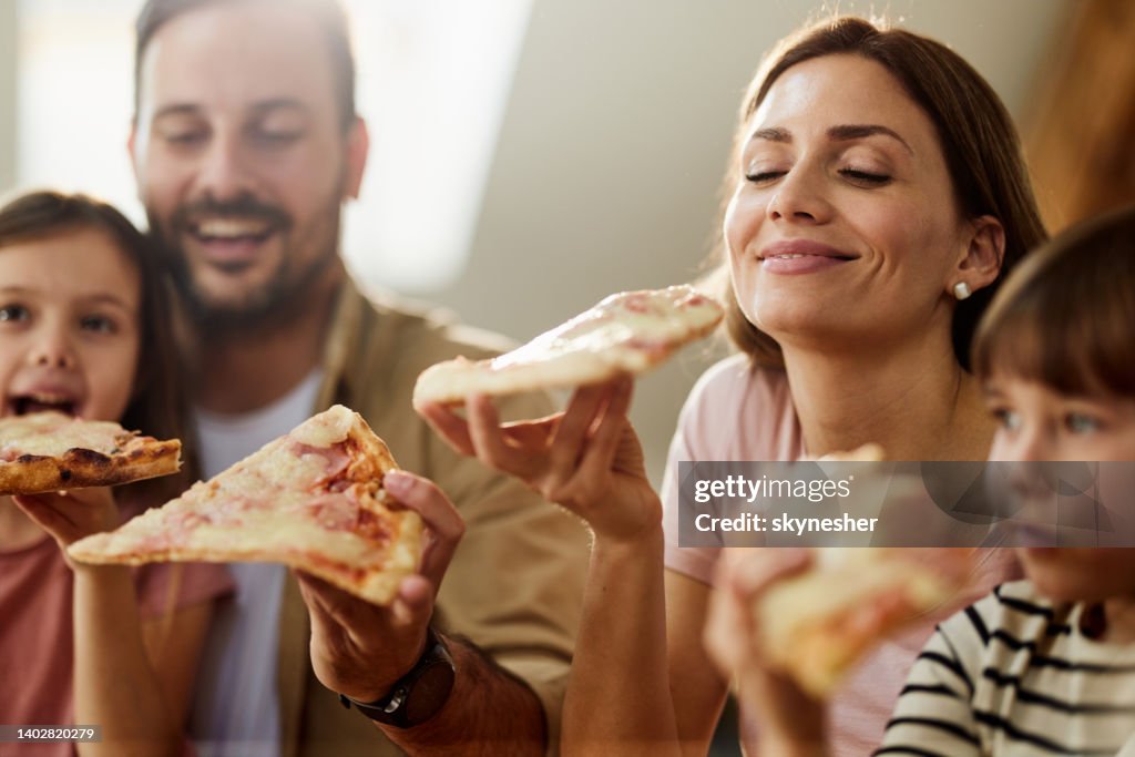 Young happy family eating pizza for lunch at home.