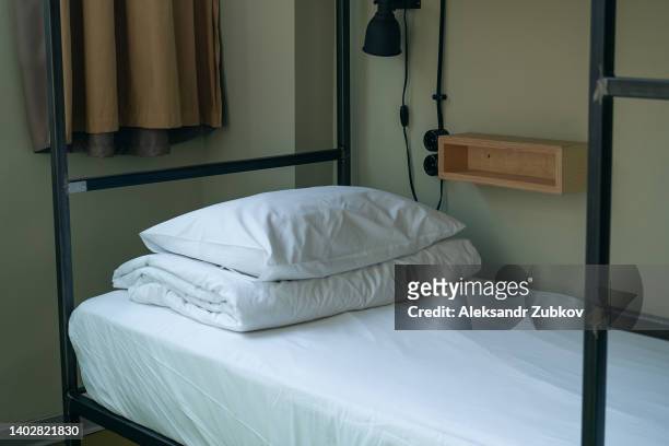 clean white bed linen on a single bed in a hostel or guest house room. booking of guests or visitors. the hostel is empty, there are no people due to the pandemic caused by the coronavirus (covid-19). the concept of tourism and travel, hotel accommodation - pousada de juventude imagens e fotografias de stock