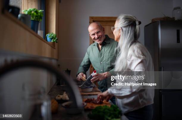 senior couple preparing meal together in their kitchen. - healthy older couple stockfoto's en -beelden