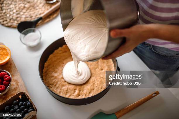 woman pouring a delicious cheese cream on cake crust - making cake stockfoto's en -beelden