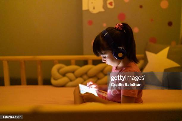 little girl using digital tablet in bed - girl rain night stock pictures, royalty-free photos & images